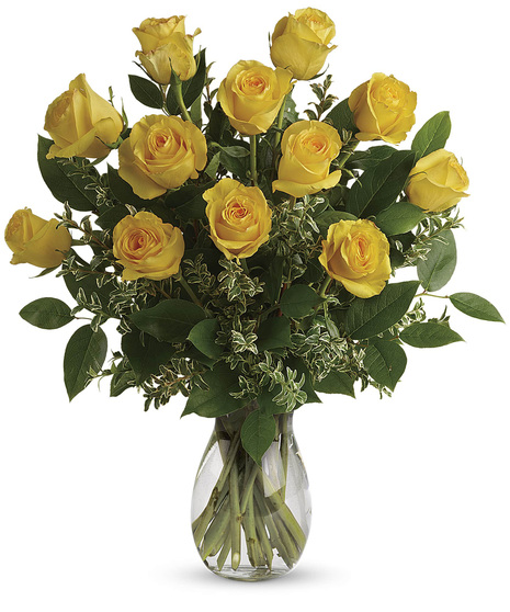 Long-stemmed yellow roses and greenery in a clear glass vase