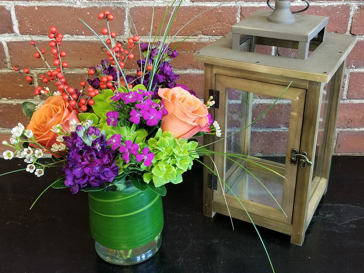 A lovely purple, orange and green arrangement, offset by an antique lantern